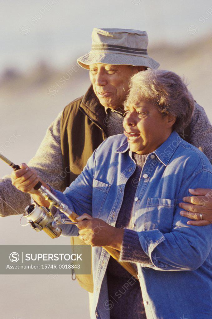 Stock Photo: 1574R-0018343 Senior man teaching a senior woman to fish
