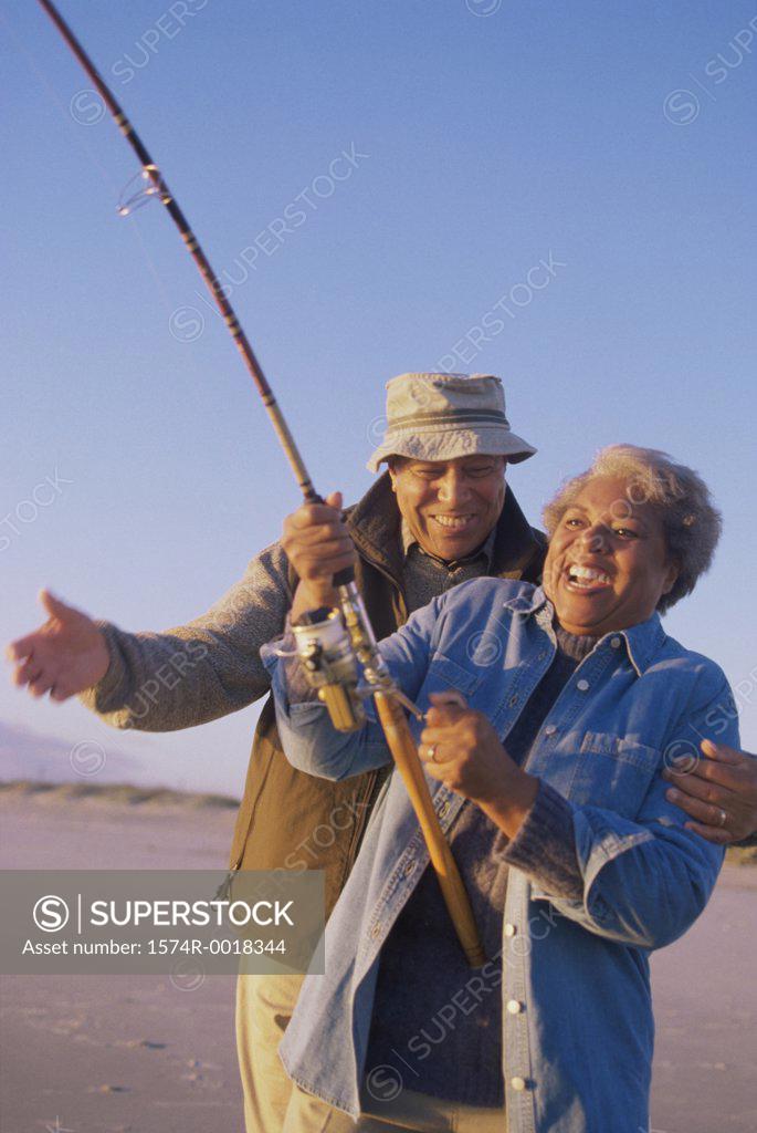 Stock Photo: 1574R-0018344 Senior woman holding a fishing rod with a senior man standing beside her