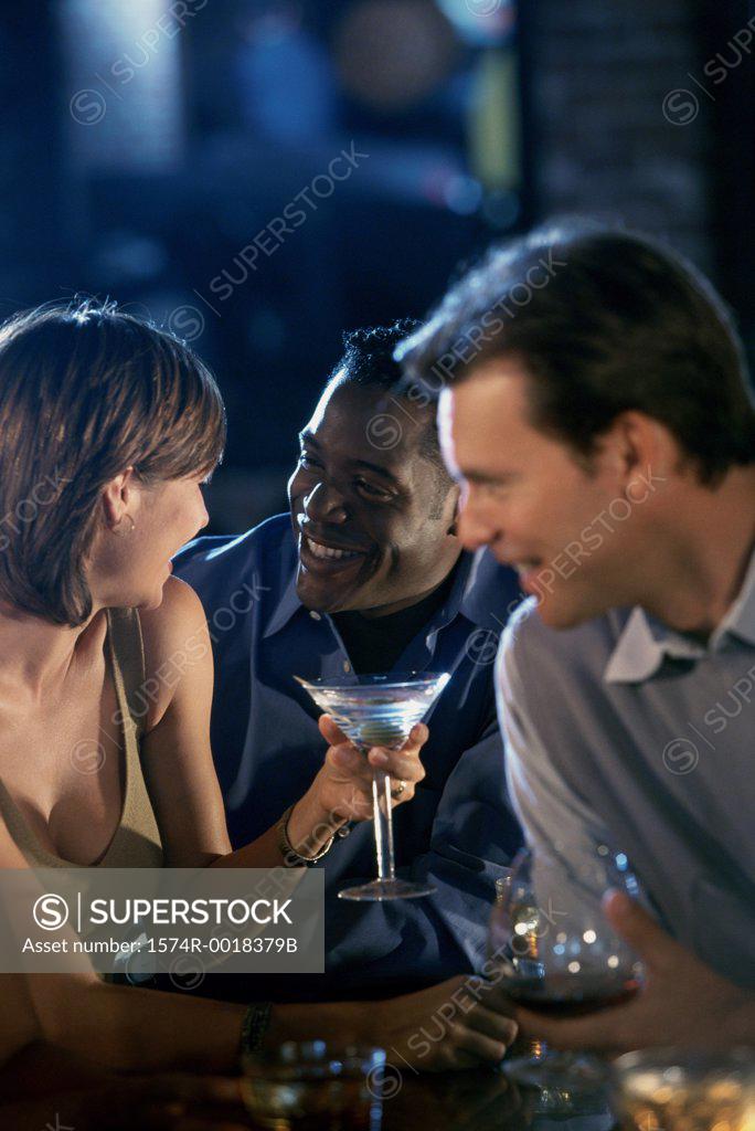 Stock Photo: 1574R-0018379B Two young men and a young woman at a bar counter