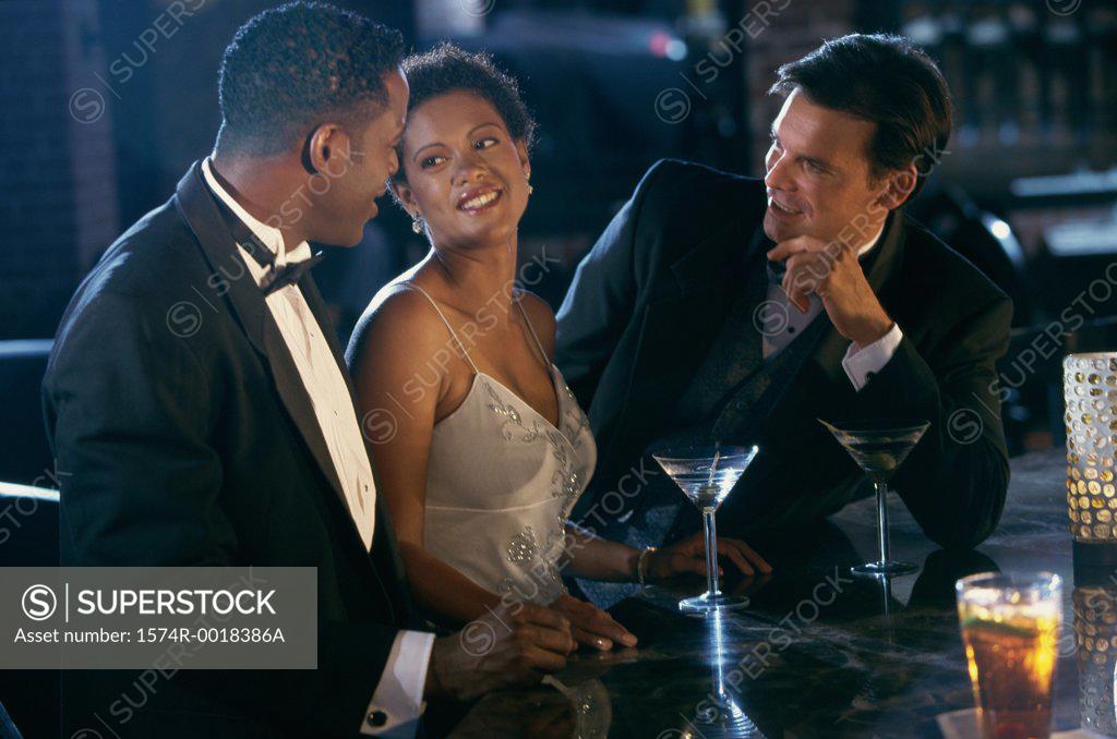 Stock Photo: 1574R-0018386A Close-up of two young men and a young woman standing at a bar