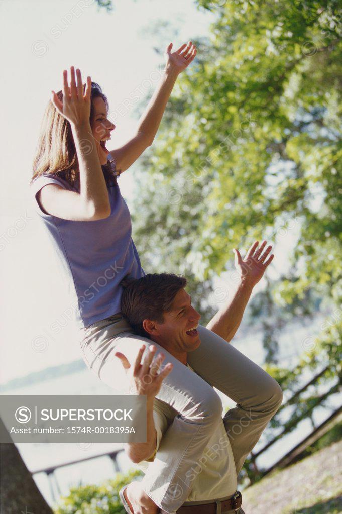 Stock Photo: 1574R-0018395A Young man carrying a young woman on his shoulders