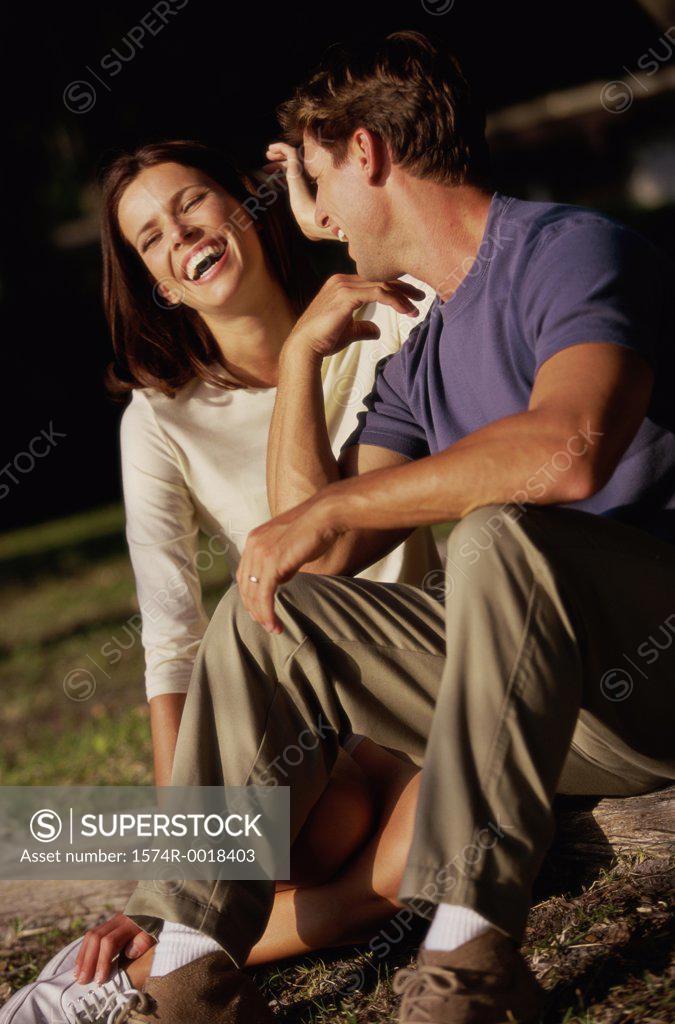 Stock Photo: 1574R-0018403 Young couple sitting together and laughing