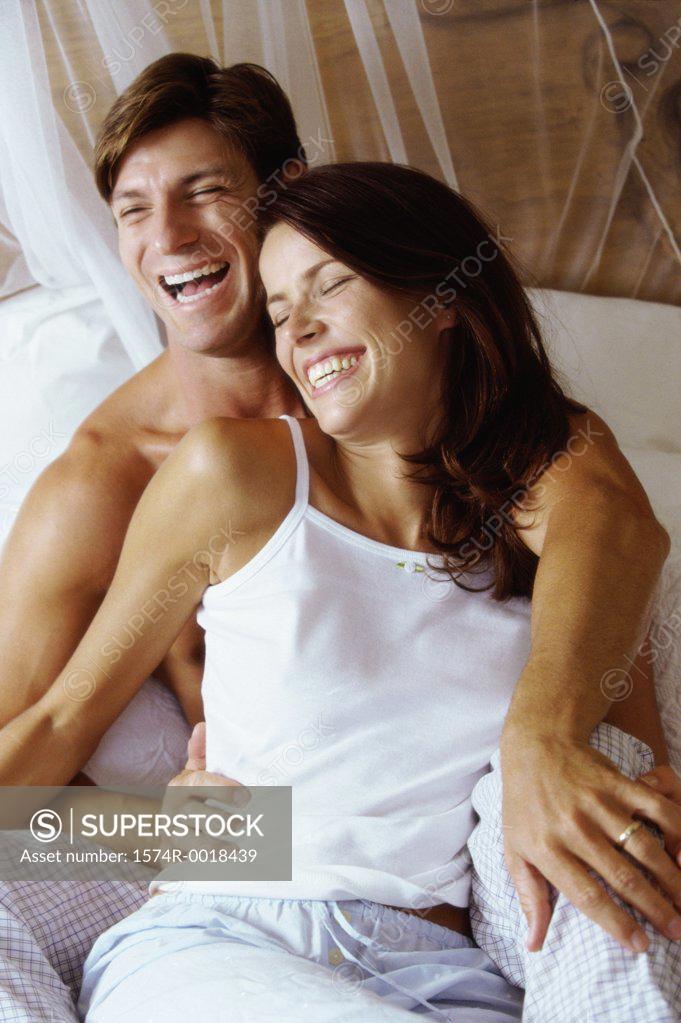 Stock Photo: 1574R-0018439 Young couple sitting on a bed