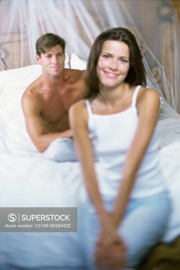 Stock Photo: 1574R-0018442C Portrait of a young woman smiling with a young man sitting behind her on a bed