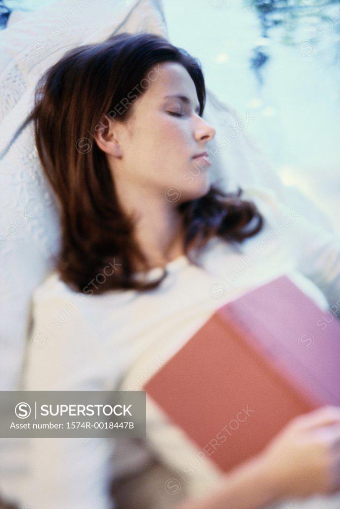 Stock Photo: 1574R-0018447B Young woman asleep with a book on her chest