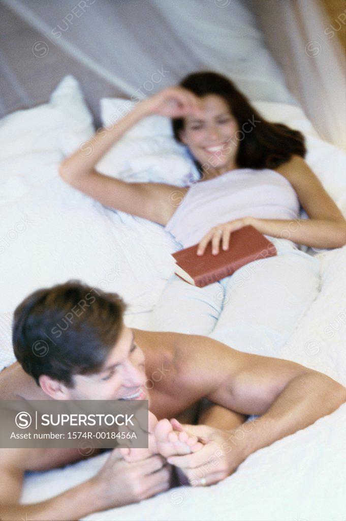 Stock Photo: 1574R-0018456A Young man massaging the feet of a young woman in bed