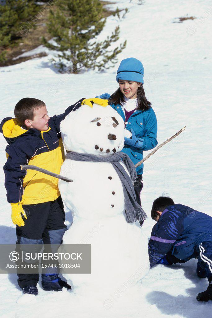 Stock Photo: 1574R-0018504 Two boys and a girl making a snowman