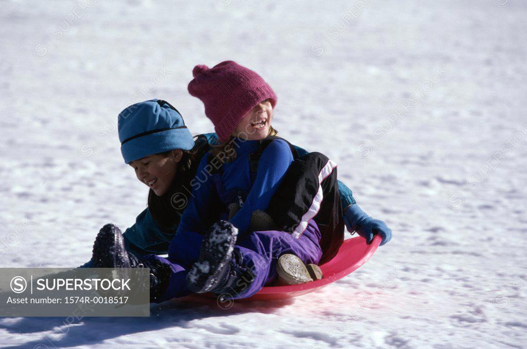 Stock Photo: 1574R-0018517 Two girls riding on a sled