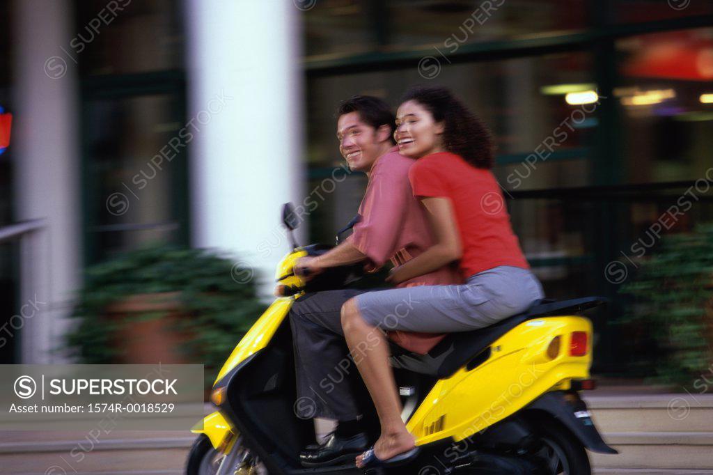 Stock Photo: 1574R-0018529 Side profile of a young couple riding a scooter