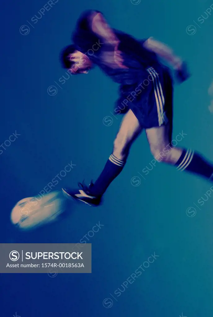 Side profile of a soccer player in mid-air kicking a soccer ball