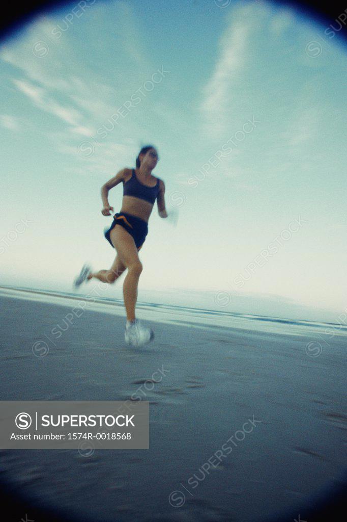 Stock Photo: 1574R-0018568 Low angle view of a young woman running on the beach