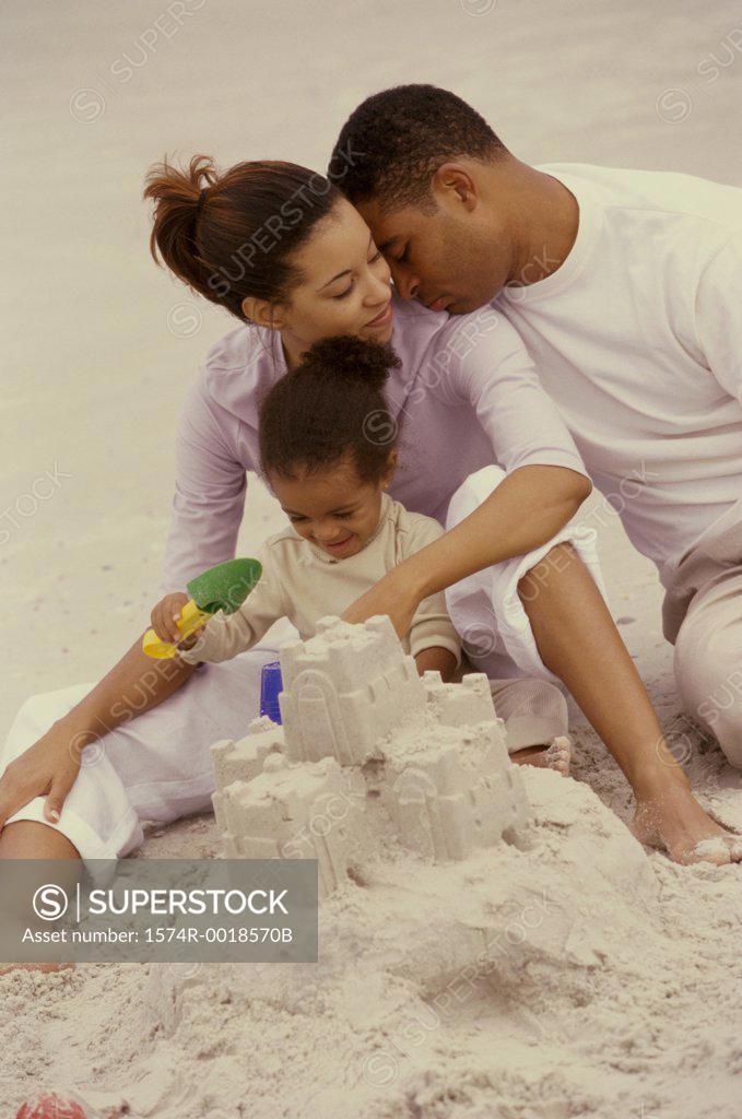 Stock Photo: 1574R-0018570B Parents making a sand castle with their daughter on the beach