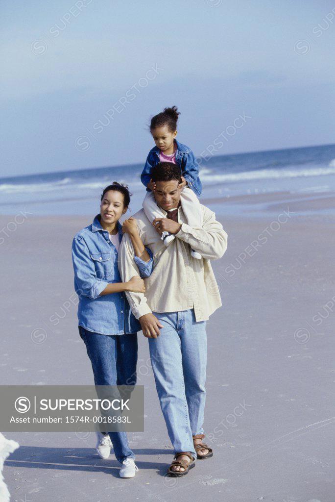 Stock Photo: 1574R-0018583L Parents smiling with their daughter on the beach