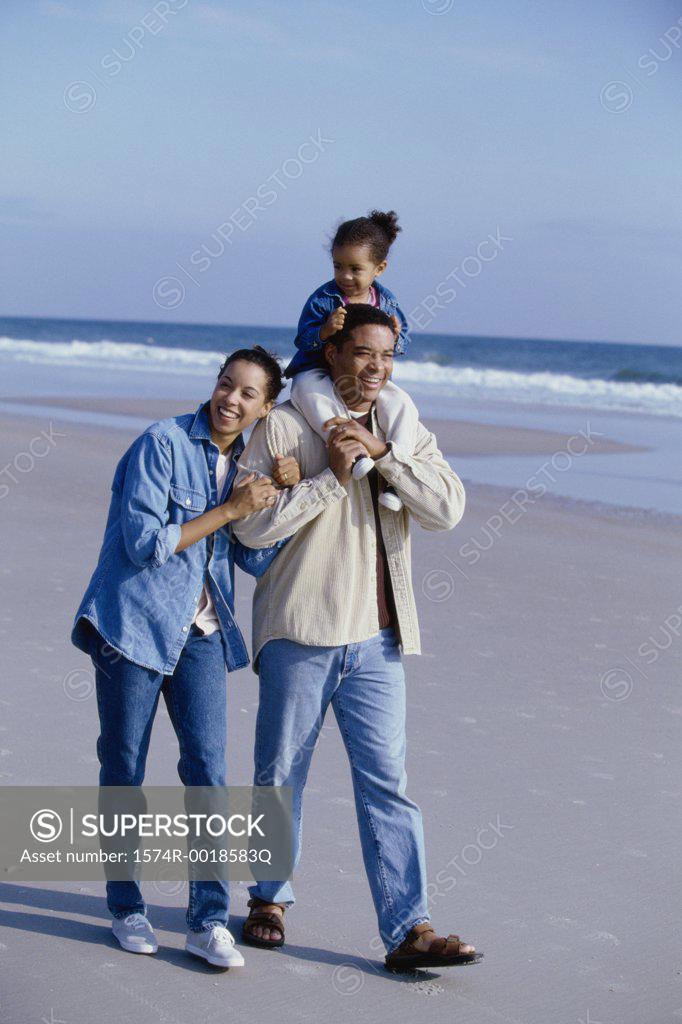 Stock Photo: 1574R-0018583Q Parents smiling with their daughter on the beach