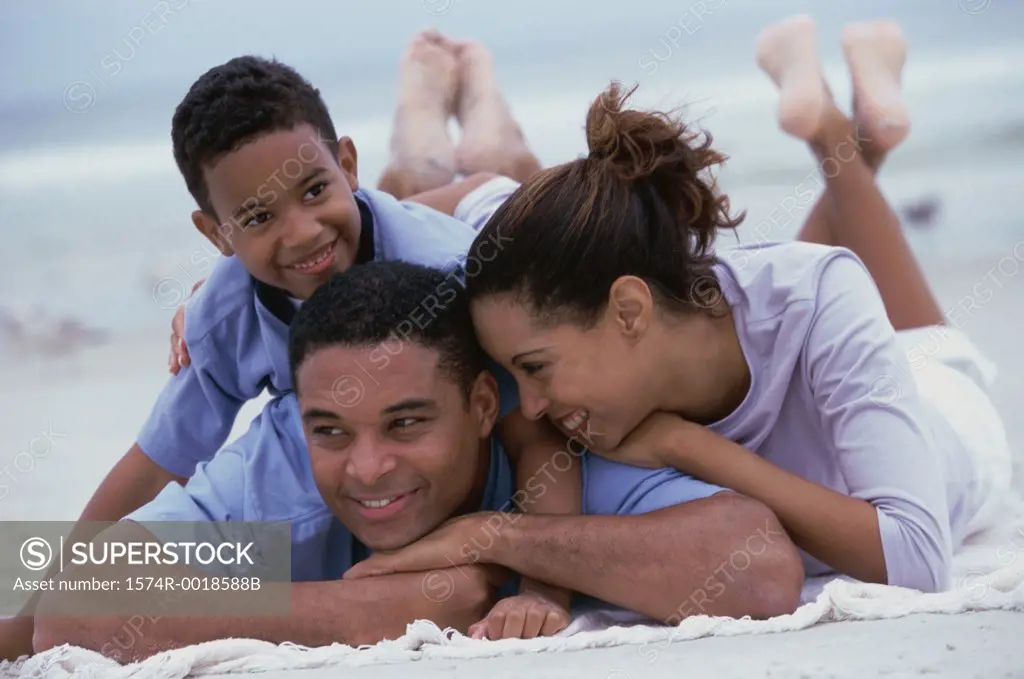 Close-up of parents smiling with their son on the beach