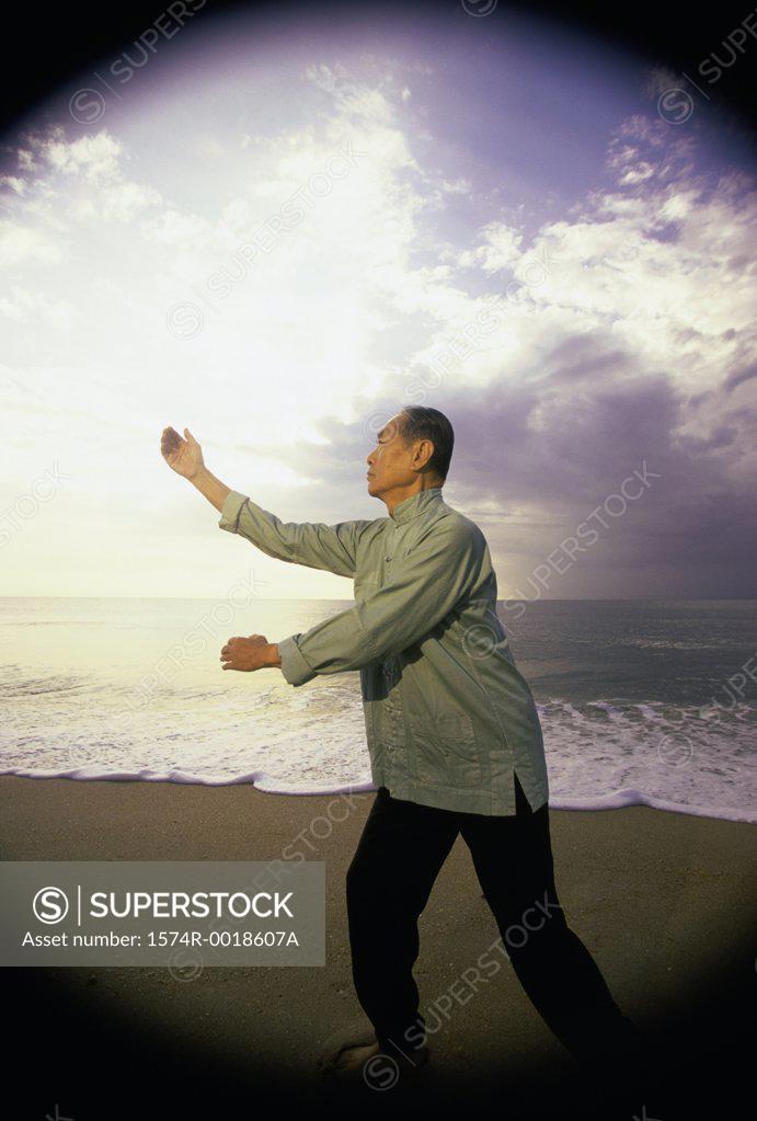 Stock Photo: 1574R-0018607A Side profile of a senior man practicing tai chi on the beach
