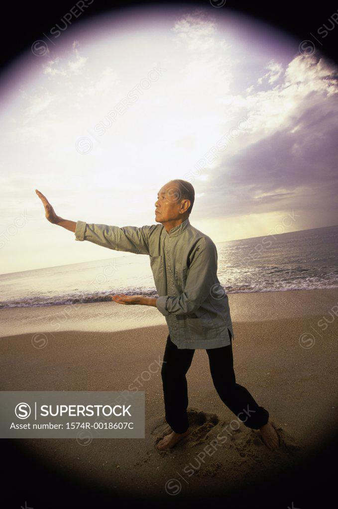 Stock Photo: 1574R-0018607C Side profile of a senior man practicing tai chi on the beach