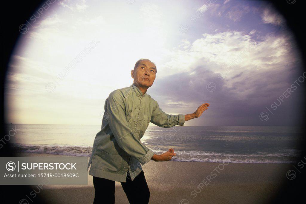 Stock Photo: 1574R-0018609C Senior man practicing tai chi on the beach