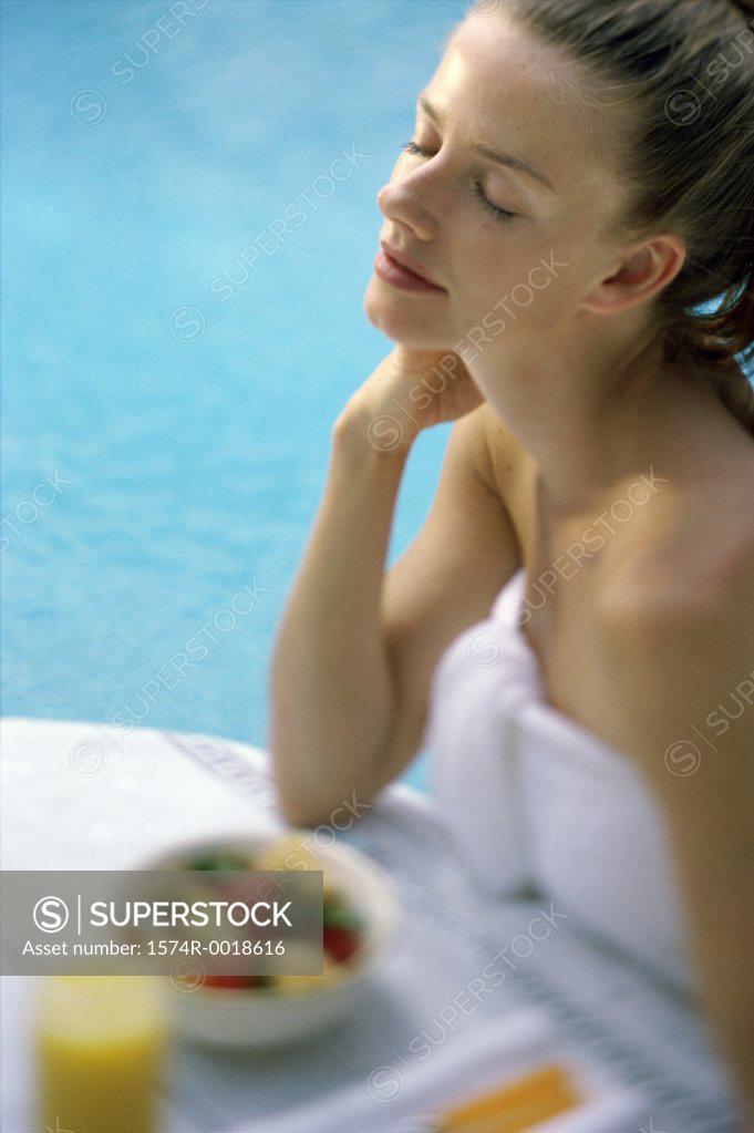 Stock Photo: 1574R-0018616 High angle view of a young woman sitting with her eyes closed at poolside