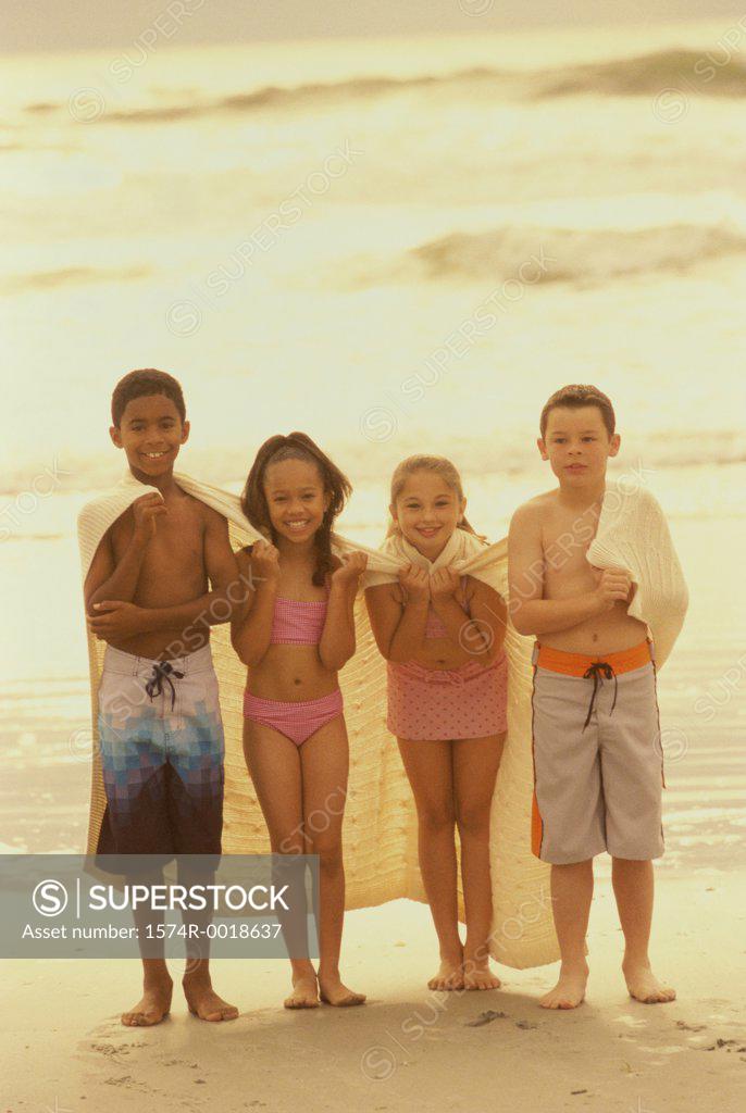 Stock Photo: 1574R-0018637 Portrait of two boys and two girls standing with a blanket on the beach
