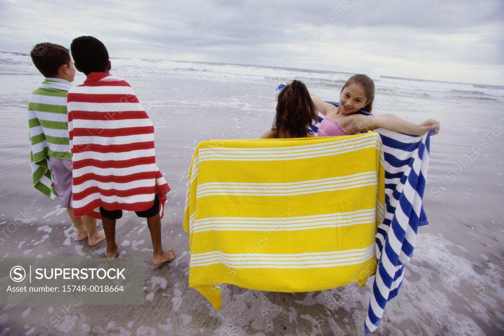 Stock Photo: 1574R-0018664 Two boys and two girls standing with towels on the beach