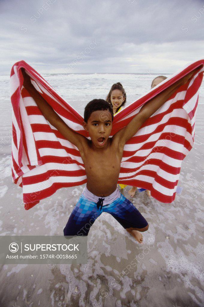 Stock Photo: 1574R-0018665 Portrait of a boy jumping with a towel on the beach
