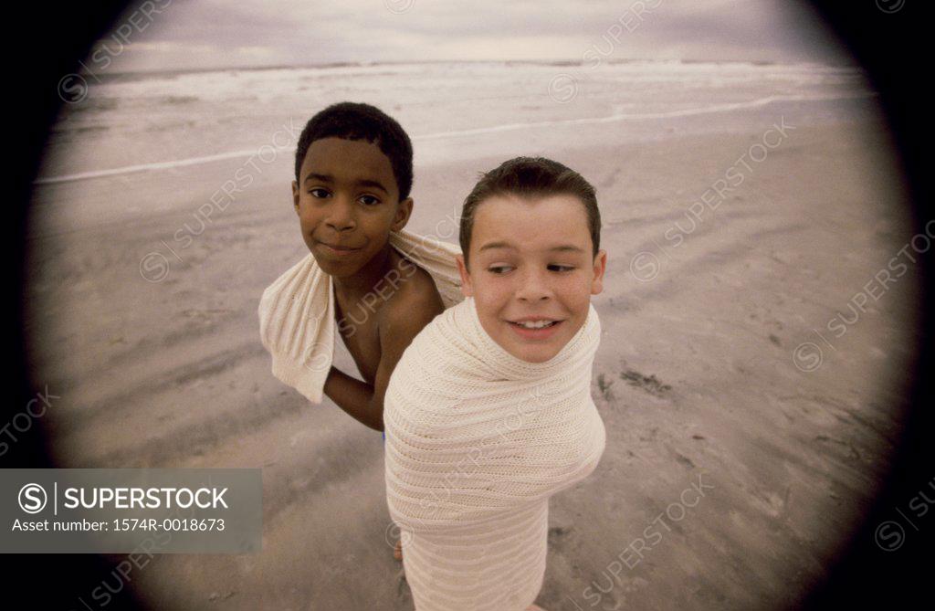 Stock Photo: 1574R-0018673 High angle view of two boys wrapped in a blanket on the beach