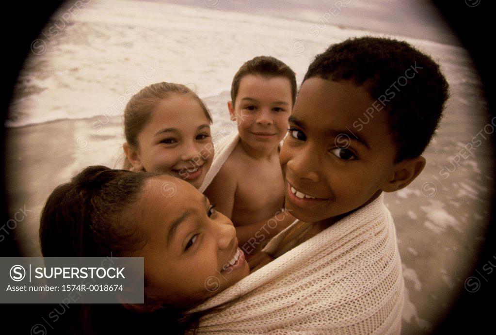 Stock Photo: 1574R-0018674 Close-up of two boys and two girls wrapped in a blanket on the beach