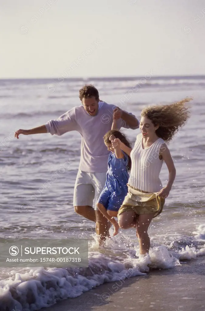 Parents and their daughter running on the beach