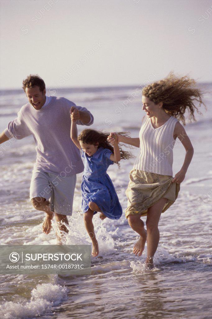 Stock Photo: 1574R-0018731C Parents and their daughter running on the beach
