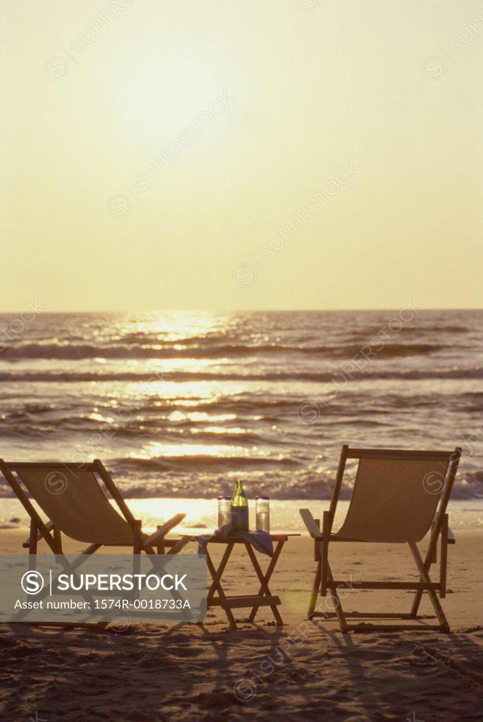 Stock Photo: 1574R-0018733A Rear view of two deck chairs on the beach at sunset