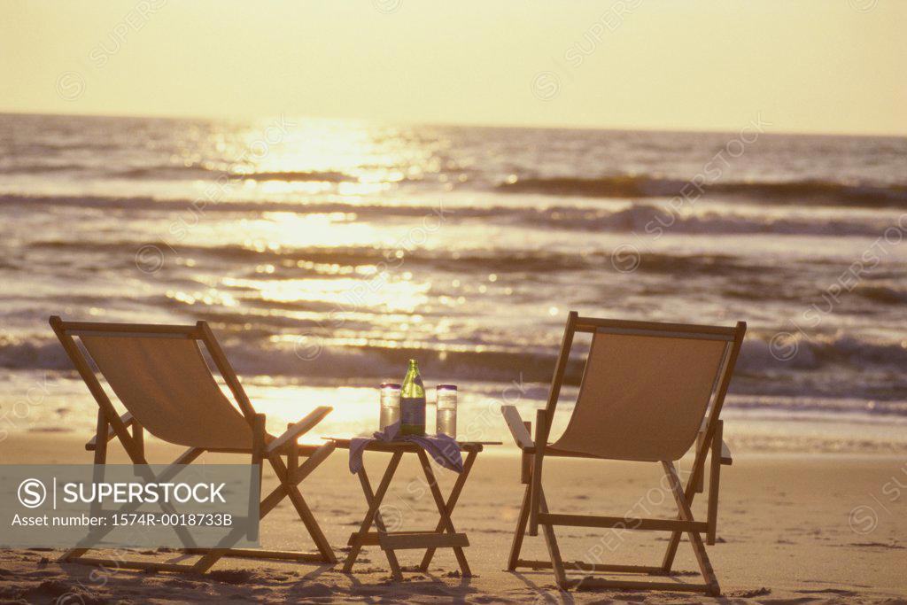 Stock Photo: 1574R-0018733B Rear view of two deck chairs on the beach at sunset
