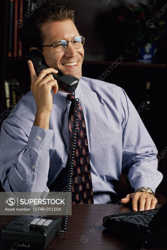 Stock Photo: 1574R-01125A Young businessman using a landline telephone on his desk