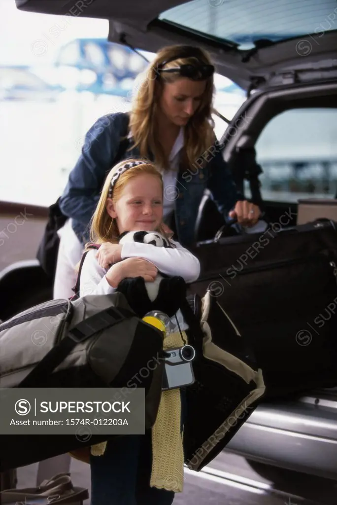Mother and daughter loading luggage into the back of a car