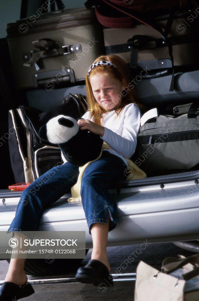 Stock Photo: 1574R-012206B Girl sitting in the back of a car and holding a teddy bear