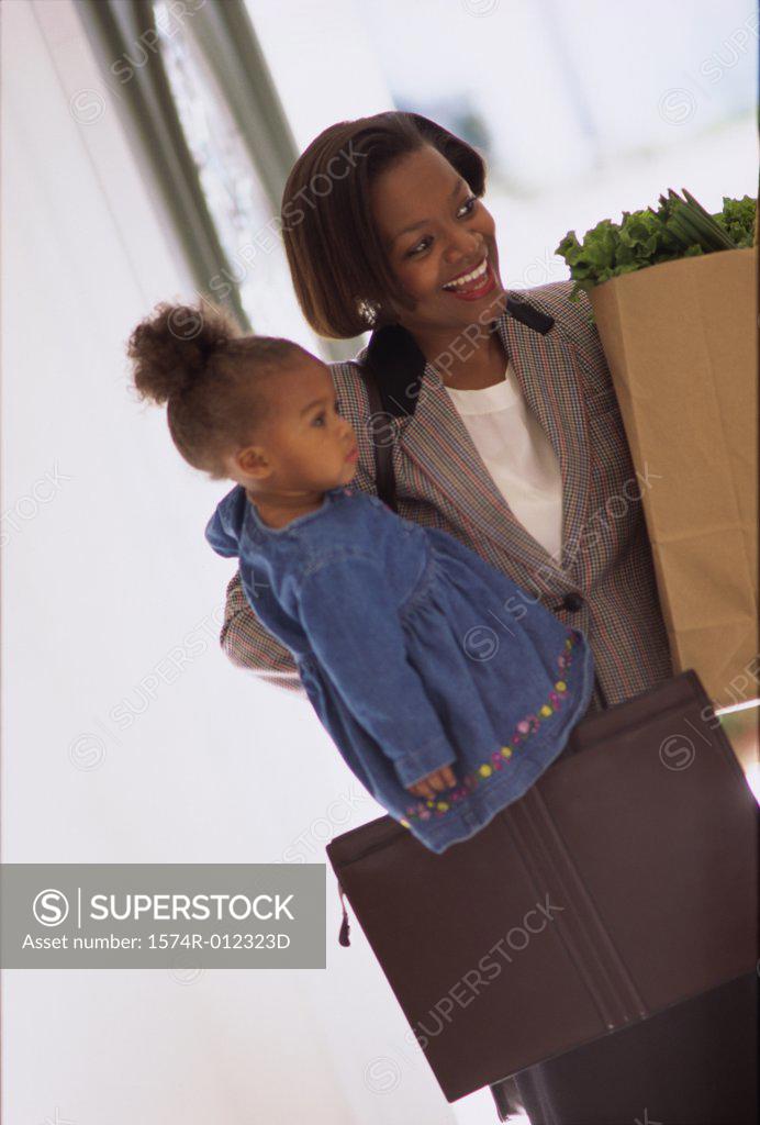 Stock Photo: 1574R-012323D Mother carrying her daughter and holding shopping bags