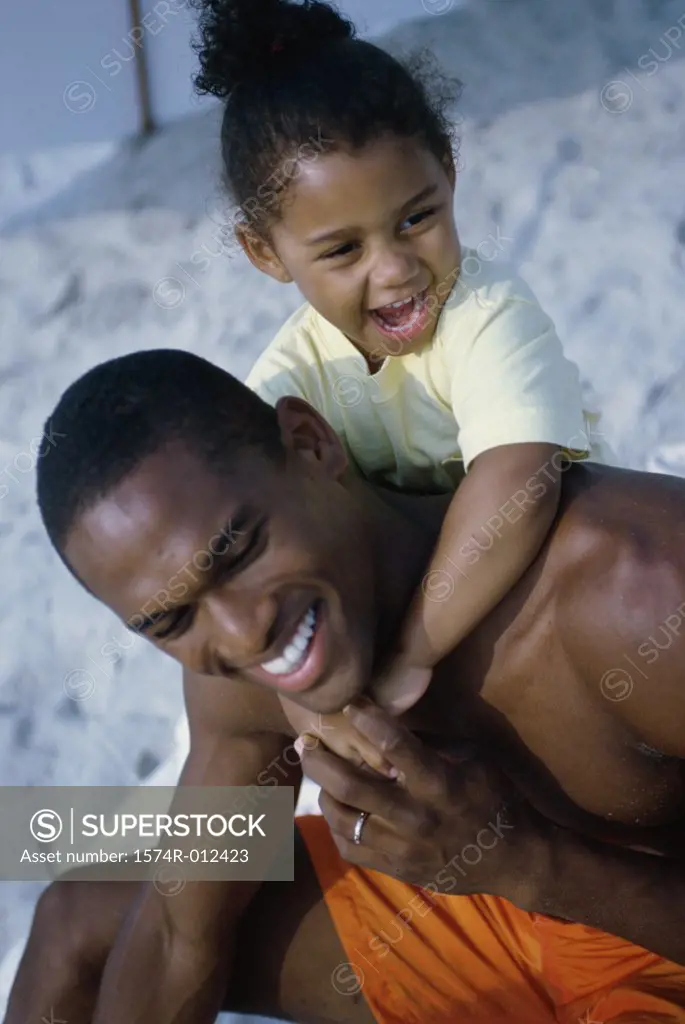 Close-up of a father and daughter smiling on the beach