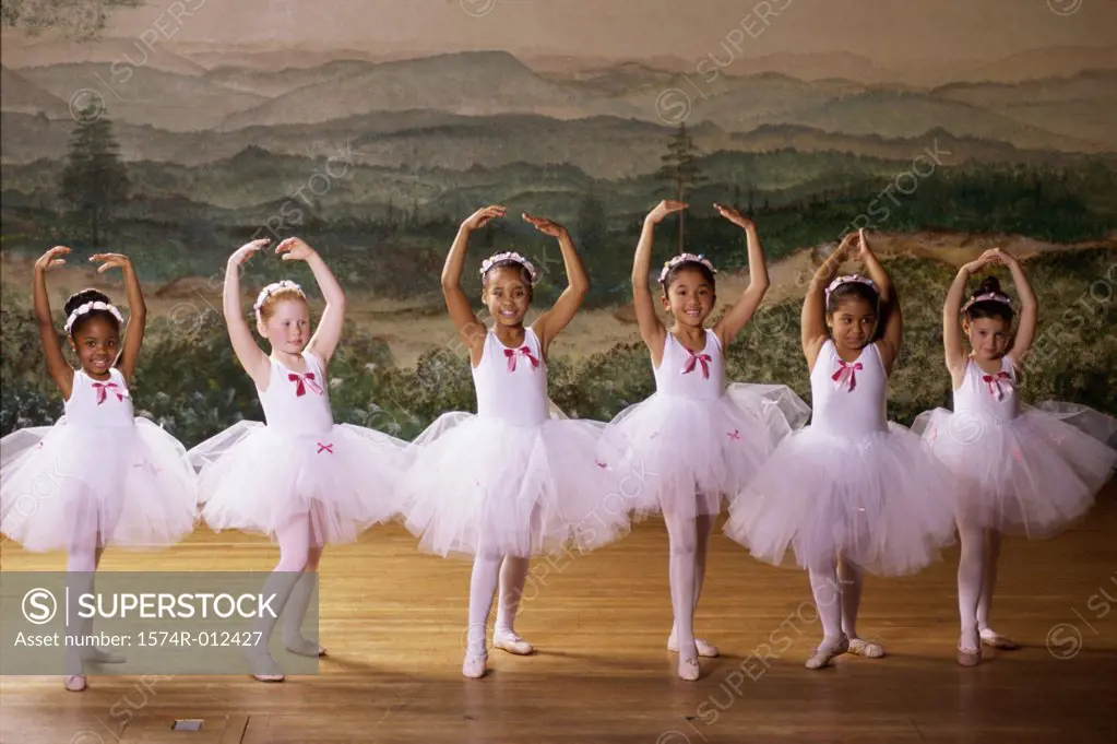 Group of ballet dancers dancing with their arms raised