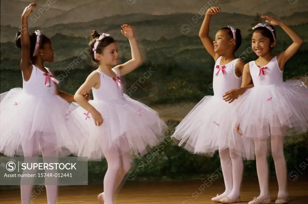 Four ballet dancers dancing with their hands raised