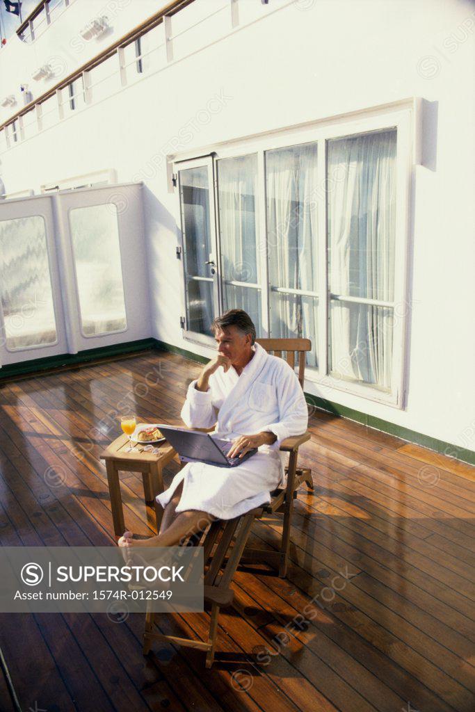 Stock Photo: 1574R-012549 Mature man sitting in a deck chair with a laptop