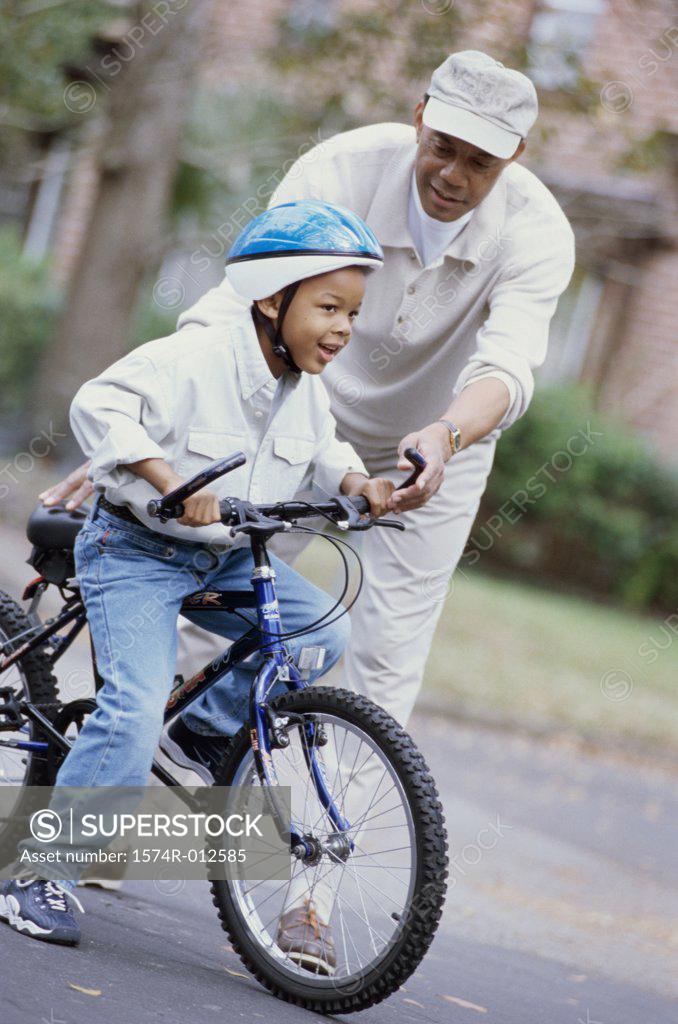 Stock Photo: 1574R-012585 Grandfather teaching his grandson ride a bicycle