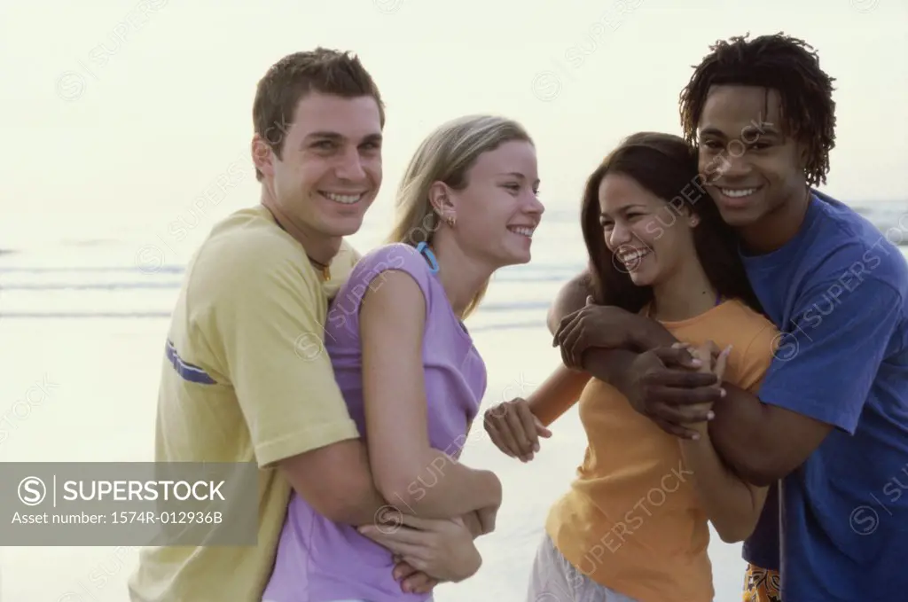 Two teenage couples embracing on the beach