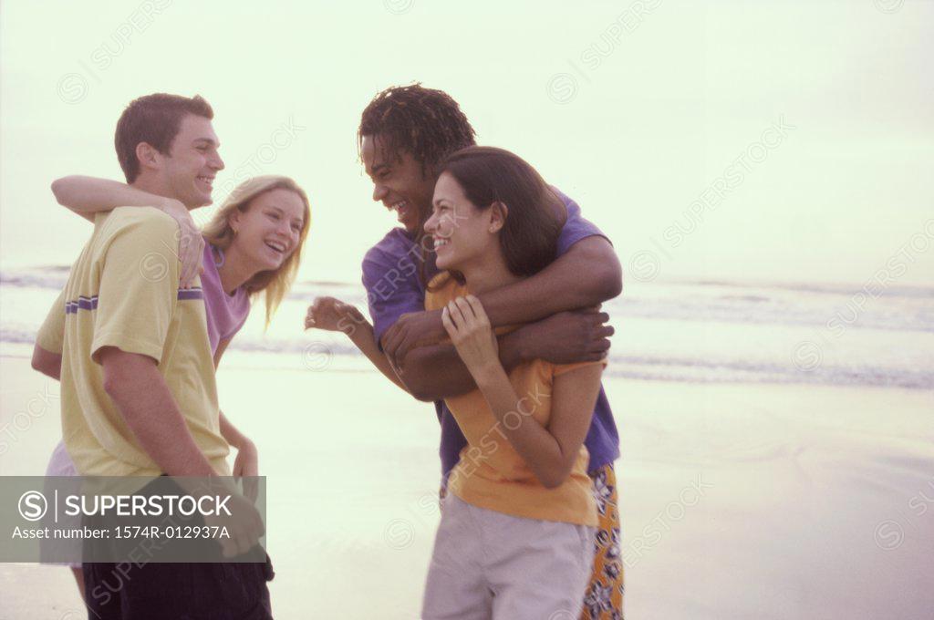 Stock Photo: 1574R-012937A Two teenage couples embracing on the beach