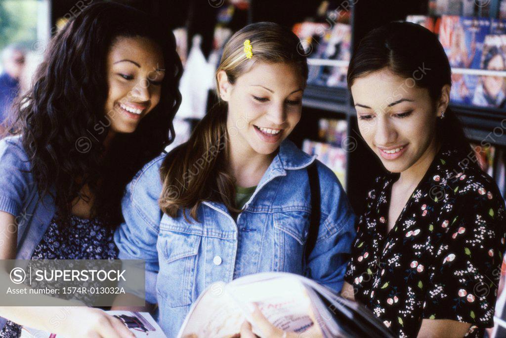 Stock Photo: 1574R-013032A Three teenage girls reading a magazine