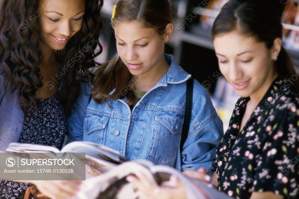 Stock Photo: 1574R-013032B Three teenage girls reading a magazine