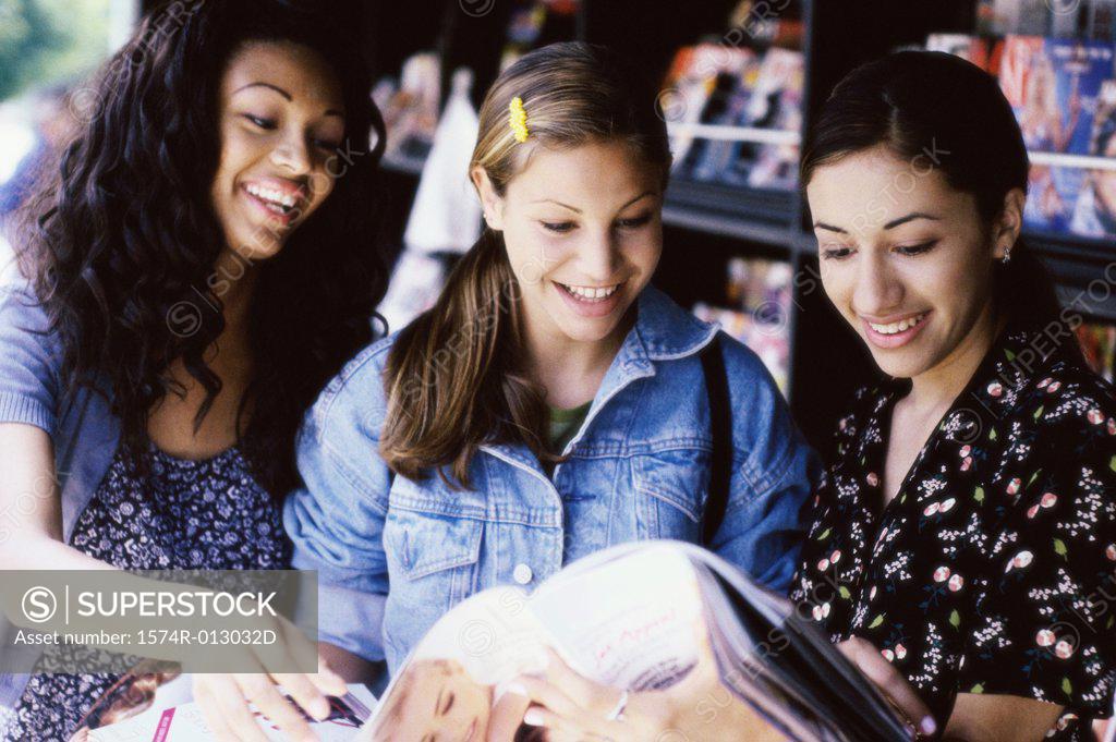 Stock Photo: 1574R-013032D Three teenage girls reading a magazine