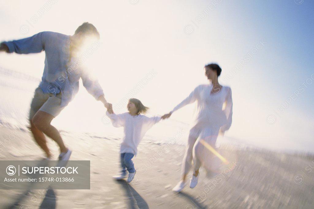Stock Photo: 1574R-013866 Parents and their daughter running on the beach