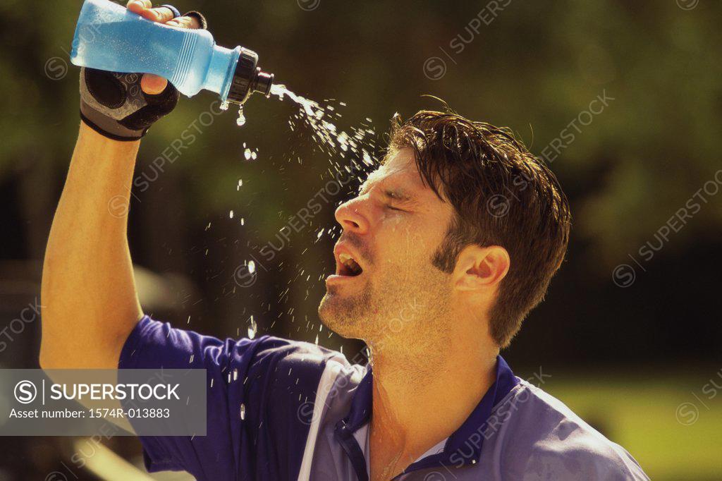 Stock Photo: 1574R-013883 Close-up of a young man squirting water on his face