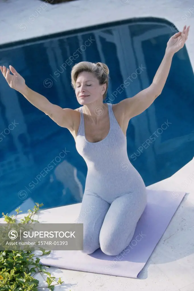 Woman meditating beside a swimming pool