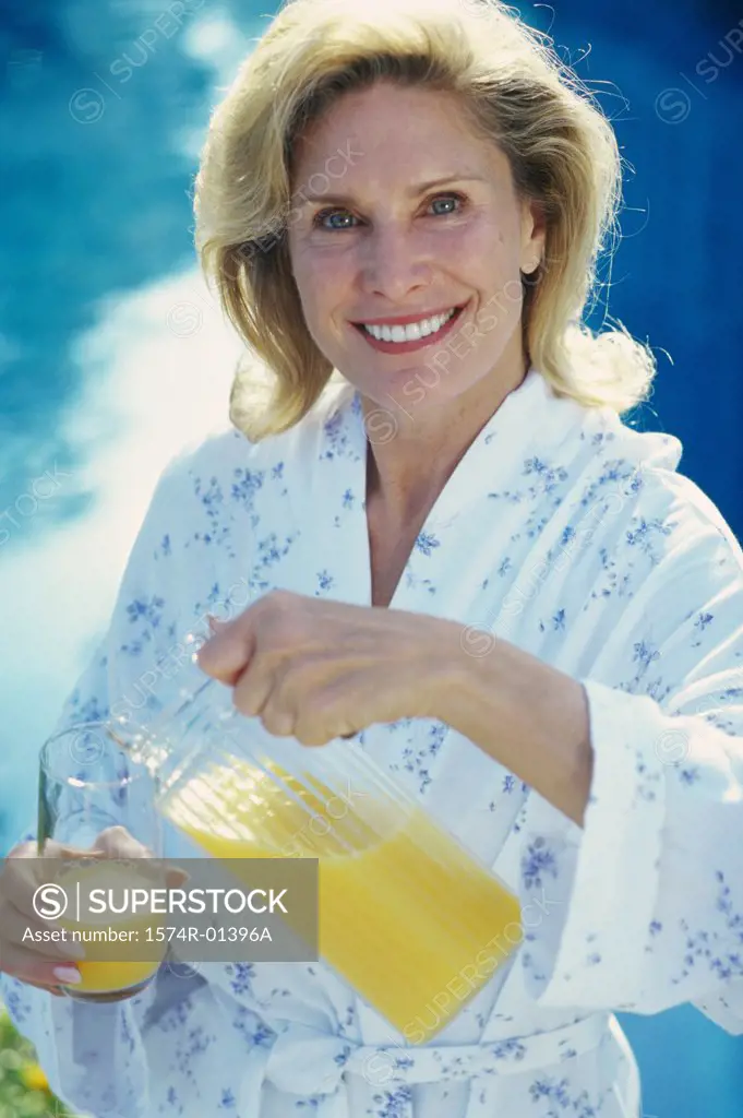 Mid adult woman pouring a glass of orange juice